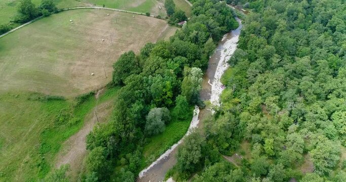 Aerial shot of river going through a forest, fields and villages nearby