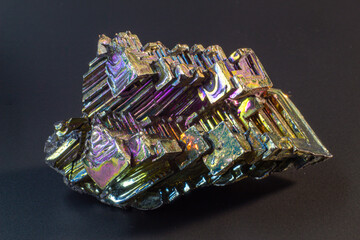 Bismuth bi close up on black surface.Interesting colour and shape crystal. Metal crystal
