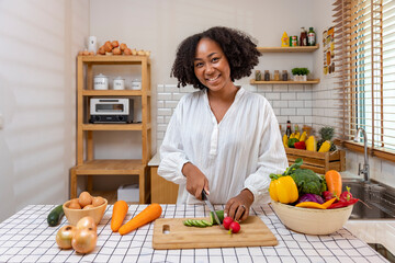 African American housewife is chopping organic cucumber to prepare simple and easy southern style salad meal for vegan and vegetarian food concept