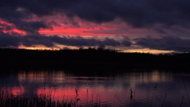 Sunset over water with reeds in tranquil place for meditation and relaxation UK 4K