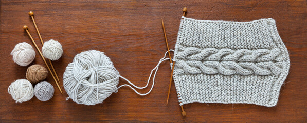 Process of knitting warm scarf with voluminous braid in middle from natural wool yarn. Balls of...