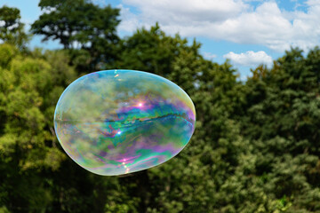 A large soap bubble floats away at a county fair in Upstate NY.  Kids at park made this colorful...