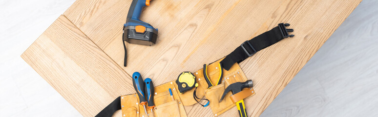 Top view of tool box with tools and electric screwdriver on table, banner