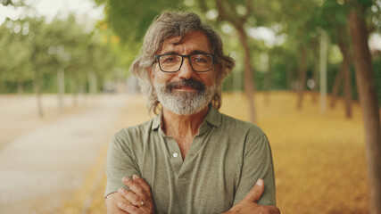 Clouse-up, friendly middle-aged man with gray hair and beard wearing casual clothes looks at the...