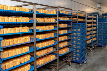 Racks with fresh bread in warehouse in industrial bakery. Finished products before being sent for sale