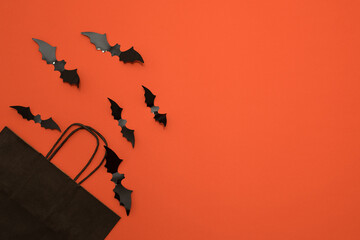 Fototapeta na wymiar happy halloween on orange background. Holiday concept, . discount offer prices. Halloween shopping, space for text, top view, black paper bag and bats