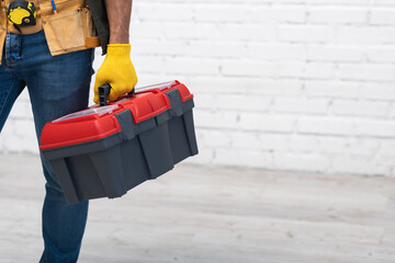 Partial view of repairman holding toolbox at home