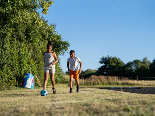 Obraz na płótnie Canvas Siblings (8-9, 10-11) playing soccer