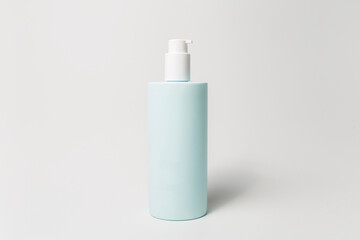Close-up of dispenser bottle with body cream of cyan color isolated on white background.