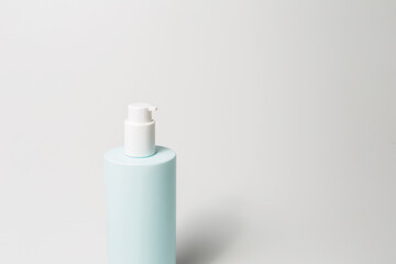 Close-up of dispenser bottle with body cream of cyan color isolated on white background.
