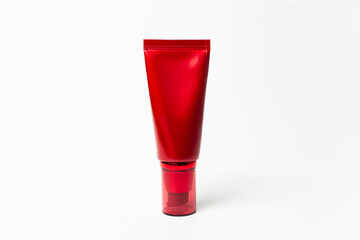 Close-up of cosmetic tube bottle of red color isolated on white background.