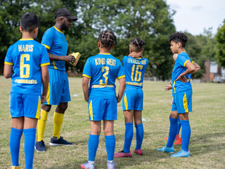 Coach meeting with kids (8-9) on soccer field