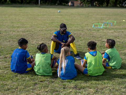 Coach giving instructions to kids (8-9) on soccer field