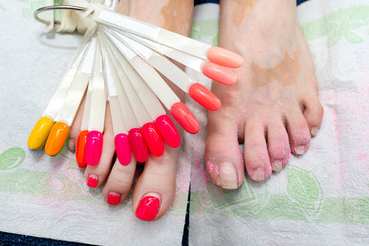 Hybrid nails painted red at the feet, a visible palette of nail colors and polished nails.
