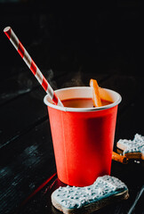 mulled wine with spices and orange slices on rustic wooden table on dark background