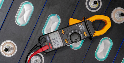 Electric vehicle lithium NMC battery. Electric car battery. Lithium-ion cell pack. Lithium NMC rechargeable battery. EV car energy storage. Voltmeter is measuring volts of electric vehicle battery.