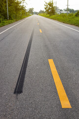 A close-up low-angle view. A long line of black rubber tires stopping violently against the paved road surface.