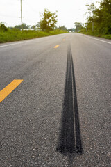 A close-up low-angle view. A long line of black rubber tires stopping violently against the paved road surface.