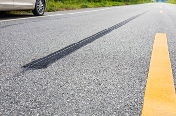 A close-up low-angle view, a long line of black tires stopping violently against the paved road surface.