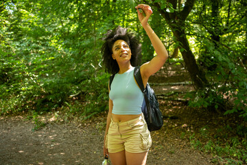 Young woman hiking in forest, looking up at trees