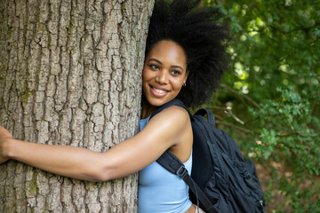 Young woman hiking in forest, hugging tree