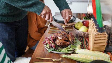 Father cutting chicken for children (8-9, 12-13) during Kwanzaa meal