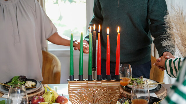Family with daughter (12-13) holding hands over Kwanzaa meal