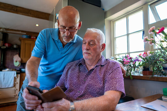 Senior Male Couple Using Smart Phone At Home