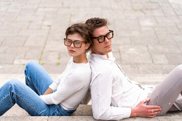 Two attractive students man and woman wearing stylish glasses sitting floor