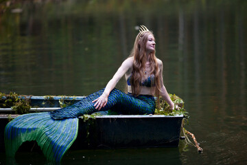 Mermaid story. The little mermaid sits in a boat. Mermaid at sunset. Mermaid's tail. Mermaid costume. The mermaid got caught in the net. Long hair.