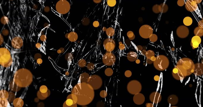 Animation of gold spots of light over light on moving shiny black plastic