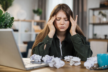 Caucasian young woman stressed about work at home office and look at something on the laptop...