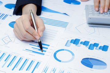 Businessman holding a profitability statistics analysis pen from a graph document in hand  to plan profit.