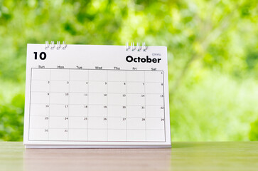 The October 2022 Calendar desk for organizer to plan and reminder on wooden table on nature background.