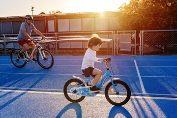 Happy smiling toddler boy riding bicycles together with grandfather having fun outdoors at warm...