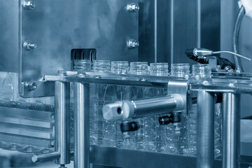 The empty water bottles  on the conveyor belt for filling process in the filling machine.