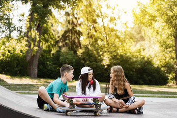Fashion children with skateboard and penny boards communicate and discuss on the sports playground....