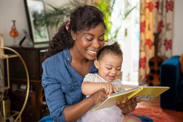 Mother reading to baby daughter (12-17 months) at home © Cultura Creative