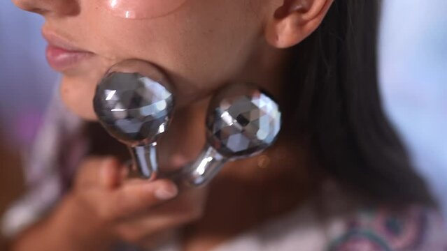 Attractive woman massaging her cheek with massage Y-shaped ball roller.