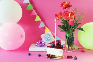 Dessert with white cream decorated with fresh berries and a burning candle, fresh roses, balloons and gifts on the table, happy birthday, holiday, congratulation, postcard