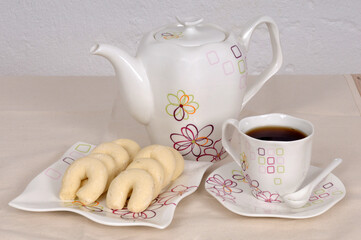There is a pot of tea and homemade sweet cookies on the dining table.