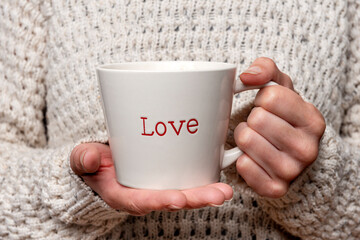 Obraz na płótnie Canvas Woman holding a mug with 'love' on it.