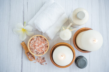 Natural relaxing spa composition on massage table in wellness center    with towels, flowers and salt, candle  on massage table in spa salon.