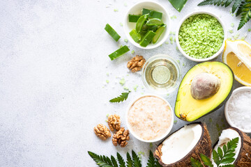 Natural cosmetic concept, homemade cosmetic. Aloe, sea salt, avocado, coconut, cosmetic oil and green leaves. Natural ingredients for healthy skin. Top view on white.