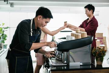 Obraz premium asian man bartender mixing and pouring coffee into cup from coffee machine at counter in small coffee shop