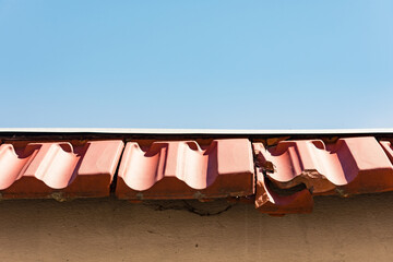 Close up to a damaged red roof tile on a blue background