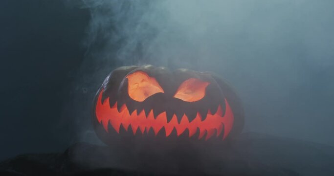 Video of halloween carved pumpkin with smoke on black background