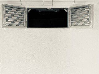 wide open window sashes with ventilation grilles in a white wall