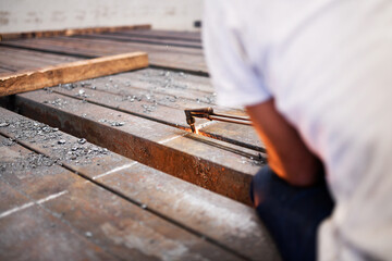 man cutting metal bars or billets with a propane and oxygen torch in the metal industry. qualified...