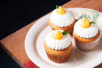 Food concept Homemade organic Lemon Meringue Cupcakes on wooden board and black background with copy space